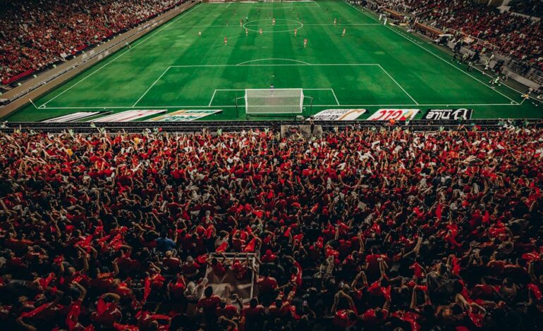 Aerial shot of a lively football match with enthusiastic fans in a packed stadium.