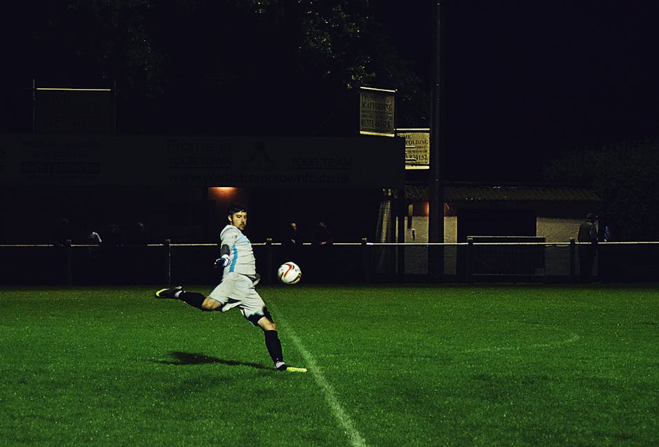 Dynamic action shot of a soccer player kicking the ball during a night game in Somerset, England.