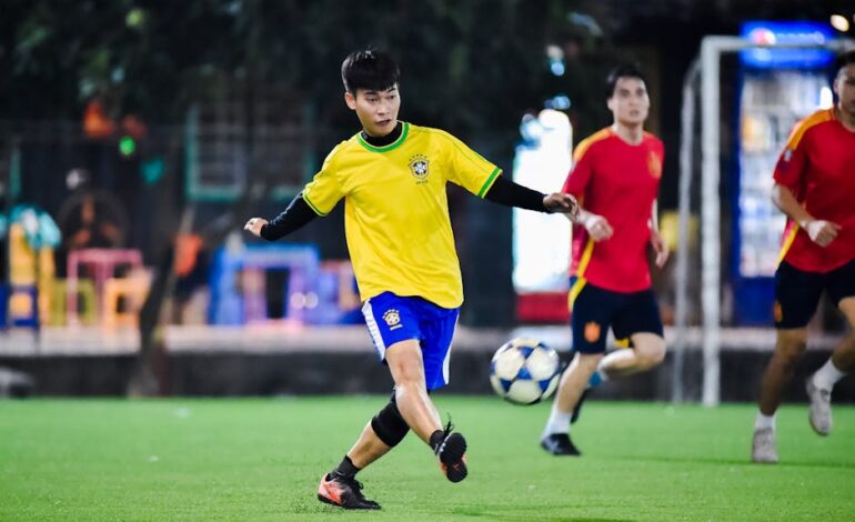 Dynamic soccer match in action at night in Hà Nội, showcasing young athletes playing on a vibrant field.
