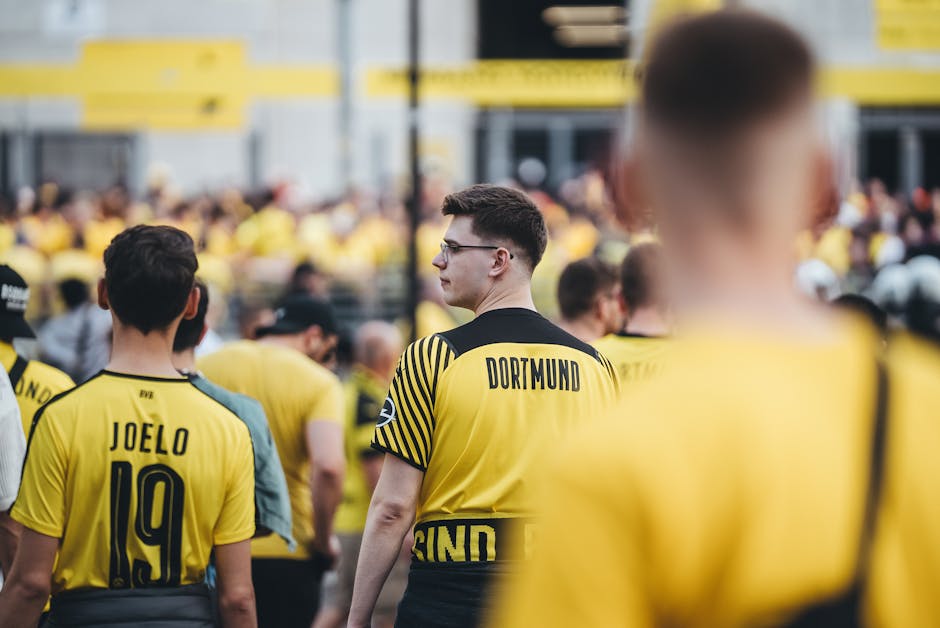 Fans in yellow jerseys gather outside a stadium, supporting their team on match day.