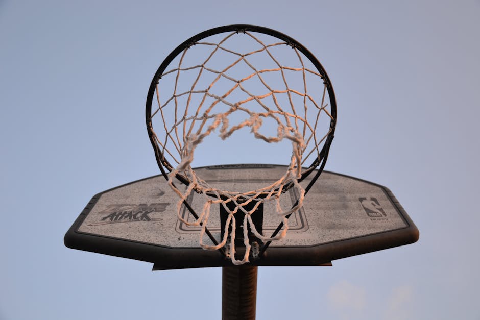 Close-up view of a basketball hoop and net against a clear sky, ideal for sports and leisure themes.