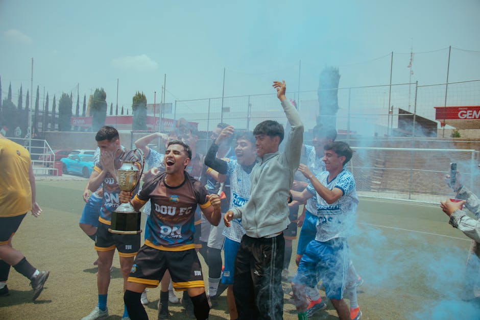 Youth soccer team jubilantly celebrates their championship victory with trophy and colored smoke.