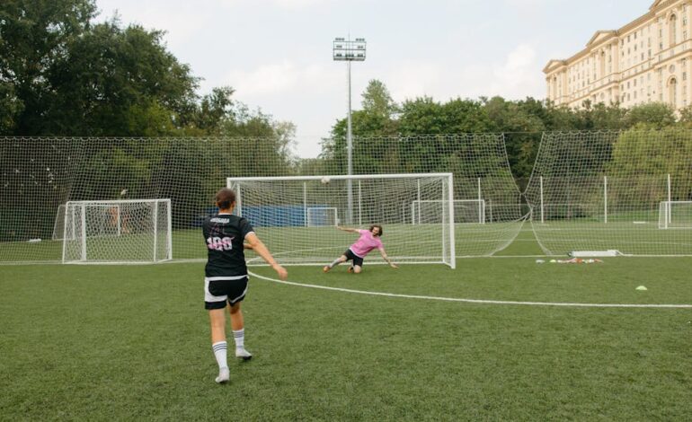 A soccer player takes an action-packed penalty shot towards the goalkeeper on a field.