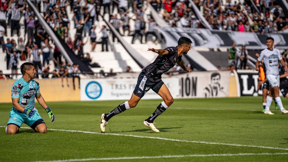 Intense soccer match with player celebrating goal in front of excited crowd.