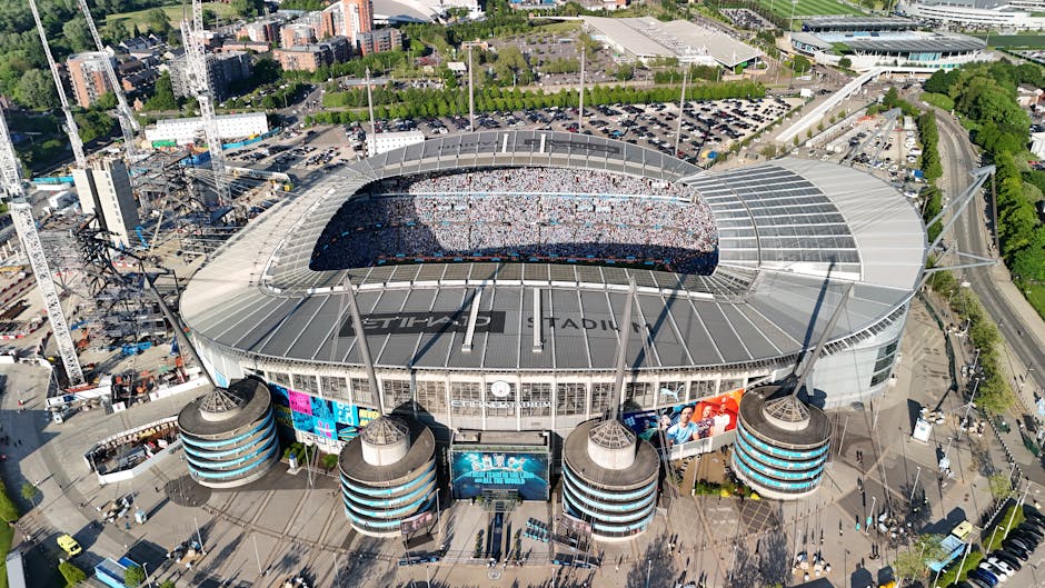 Drone shot of a packed Etihad Stadium in Manchester, England, showcasing a vibrant cityscape.