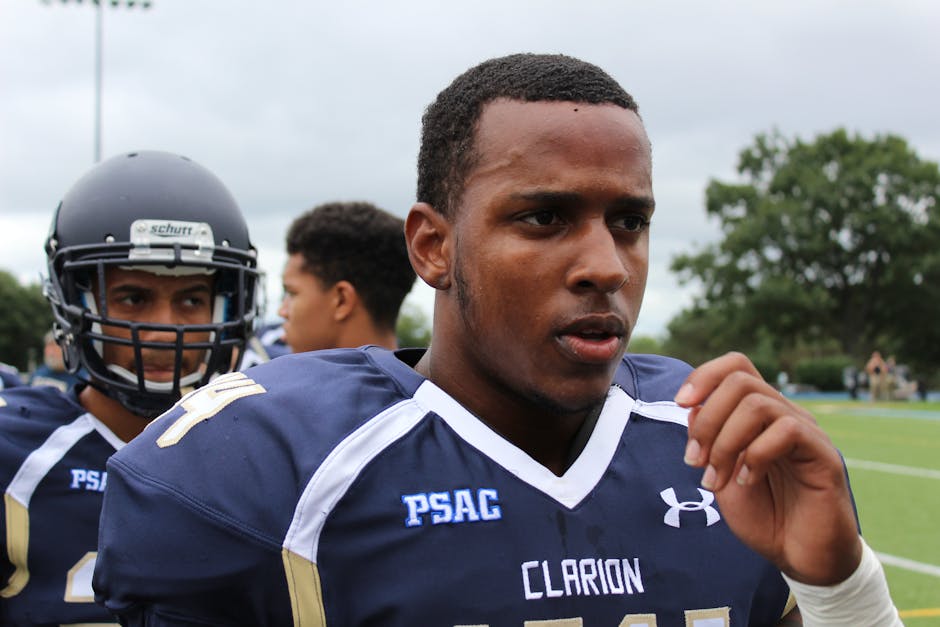Close-up of a focused football player in a PSAC game, wearing navy uniform and helmet.