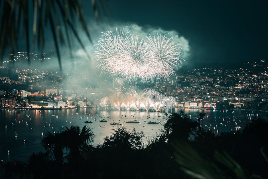 Nighttime fireworks display over Lugano, Switzerland, lighting up the lake and cityscape.