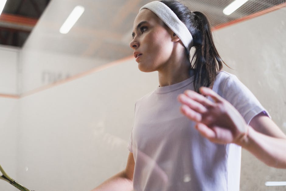 Focused female squash player in intense moment during indoor game, showcasing athleticism and determination.