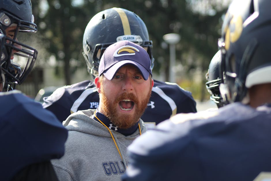 A football coach passionately instructs his team during an intense outdoor practice.