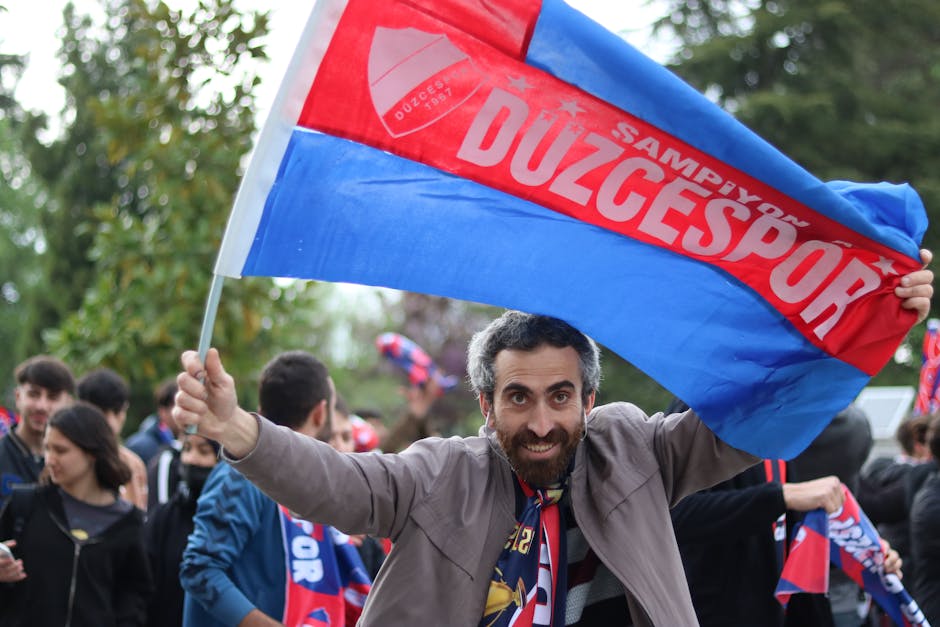 Excited Duzcespor supporters celebrate with flags outdoors, showcasing team spirit and joy.