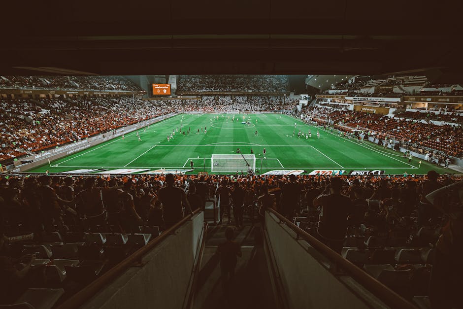 Aerial shot of a thrilling football match in a packed stadium, with enthusiastic fans.