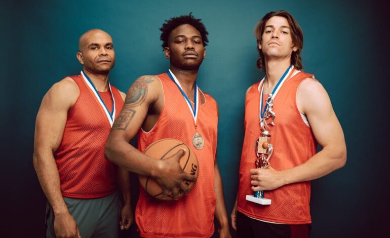 Three basketball players posing confidently with medals and a trophy in a studio.