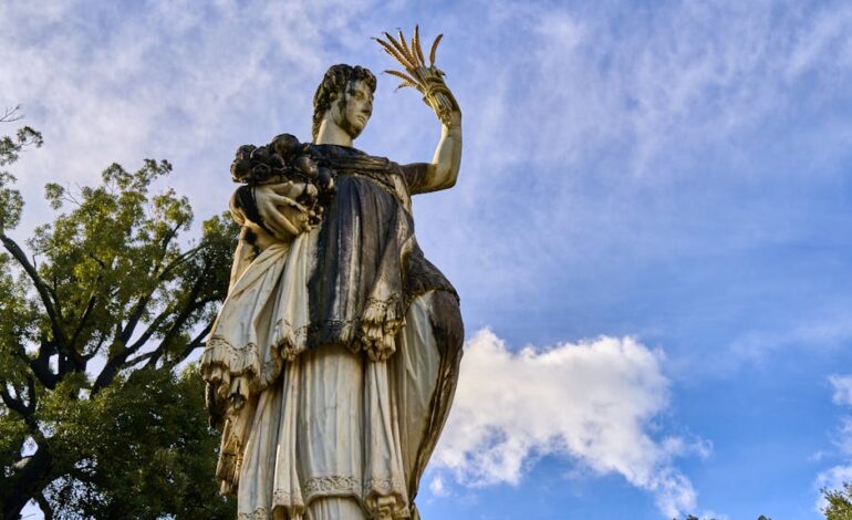 A majestic marble statue with an elegant pose, set against a clear blue sky with clouds.