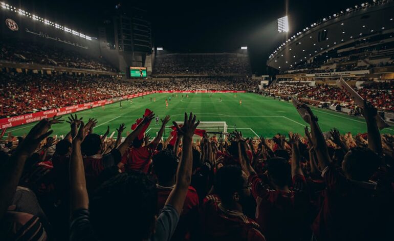 Lively football match with cheering fans in Abu Dhabi stadium at night.