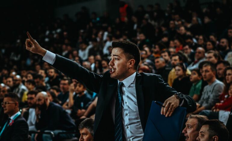 Motivated coach directing during a tense basketball game in a crowded arena.