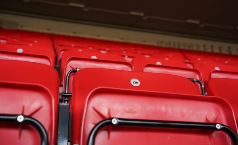 Close-up of numbered red stadium seats in an empty arena, highlighting seats at a famous stadium.