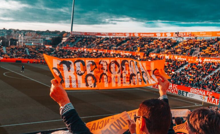 Energetic crowd at Girona FC stadium holding a vibrant banner during a football match.