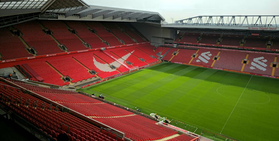 Aerial view of Anfield Stadium, Liverpool, showcasing its empty red seats and green pitch.