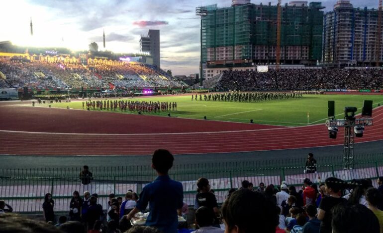 Crowd enjoying a lively sports event at a Cambodian stadium in the evening.