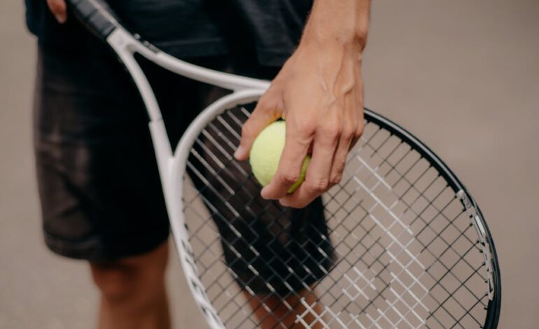 Detailed view of a tennis player holding a tennis ball and racket, preparing for a serve.