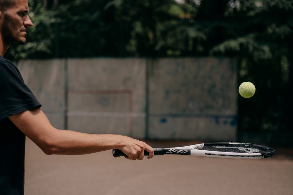 Side view of a male tennis player practicing outdoors, focusing on technique.