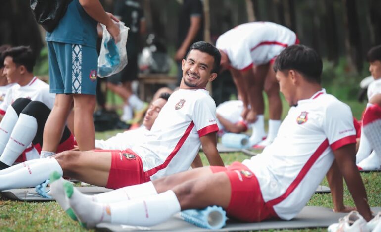 Soccer players in Jakarta relaxing on mats during a practice session outdoors.
