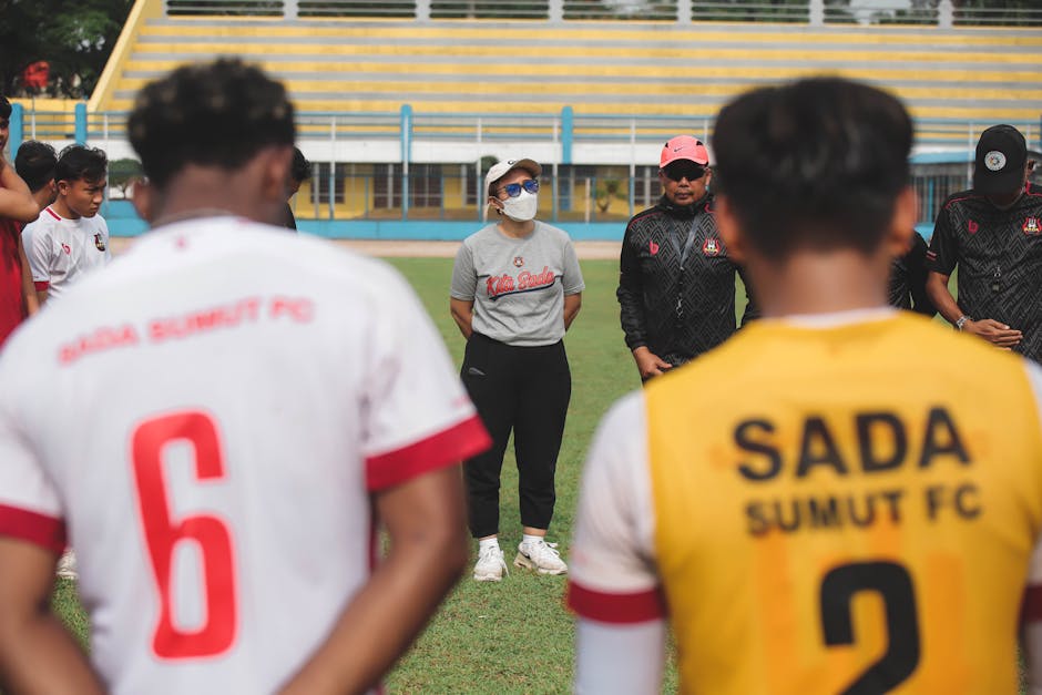 Football team gathered in an outdoor field huddle in Jakarta, Indonesia.