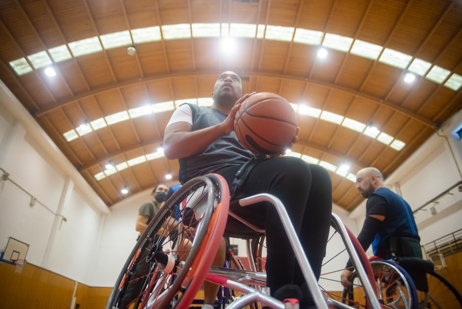 Athletes engage in wheelchair basketball training in a well-lit indoor gym.
