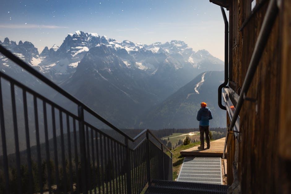 Person enjoying starry night view over Italian Alps from a lodge balcony.