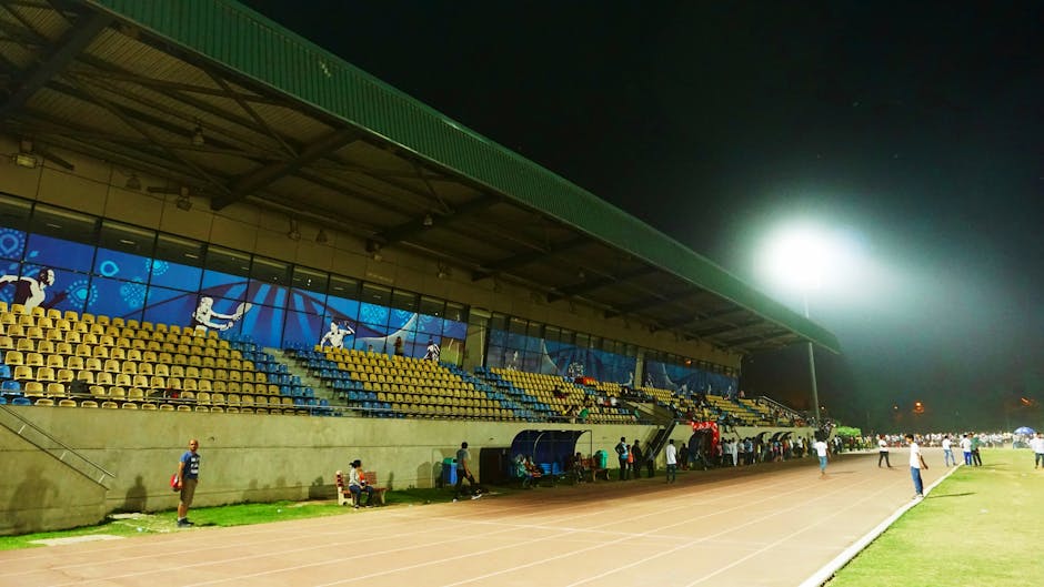 A vibrant night sports event at an outdoor stadium with athletes and spectators enjoying the game.