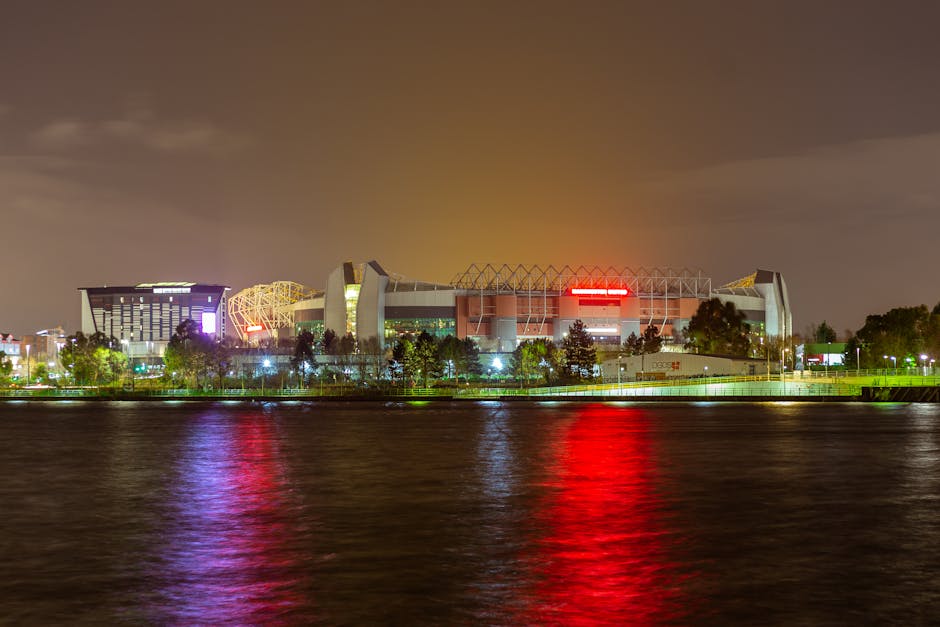 A stunning view of Old Trafford Stadium reflected in water at night in Manchester, UK.