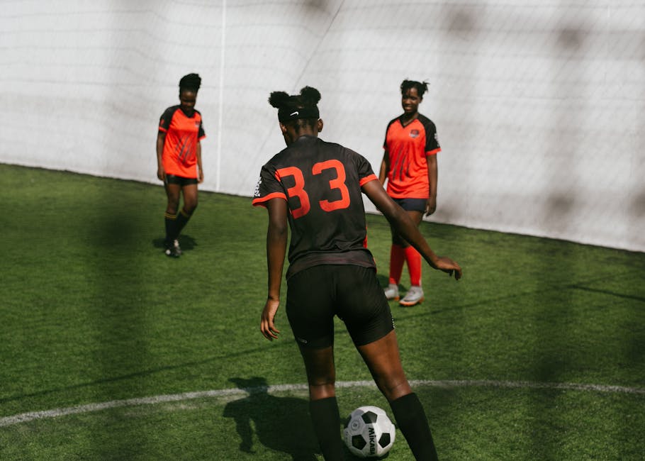 Three female soccer players practicing on an outdoor field during a sunny day match.