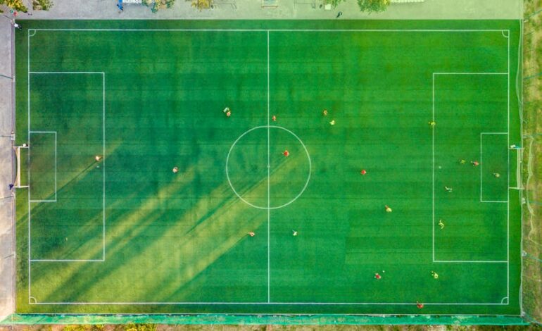 Aerial shot of a soccer game with players on a vibrant green field.