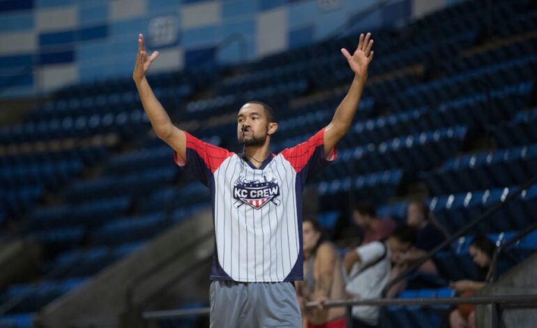 Referee signals during a basketball game at an indoor stadium wearing sports attire. Action capture.