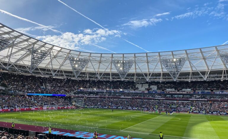 A packed London Stadium hosts a thrilling soccer match, with vibrant atmosphere and engaged crowd.