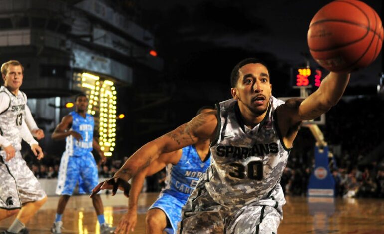 Intense basketball game with athletes in action on an outdoor court during nighttime.