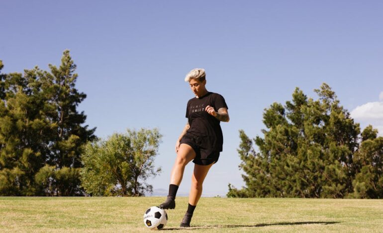 A woman playing soccer on a grass field under a clear sky, showcasing energy and focus.