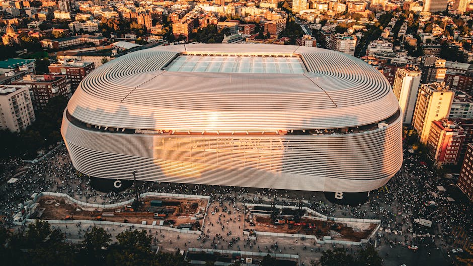 Stunning aerial shot of the Santiago Bernabéu Stadium, Madrid during sunset with bustling cityscape.