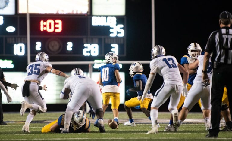 Athletes in action during a thrilling late-night American football match in a stadium.