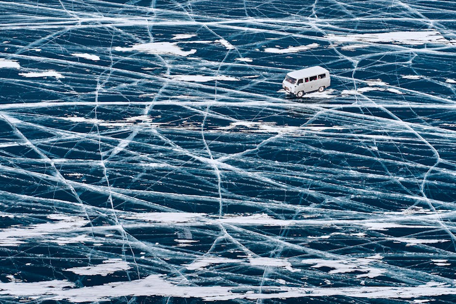 A van driving across the icy surface of Lake Baikal with intricate ice patterns.
