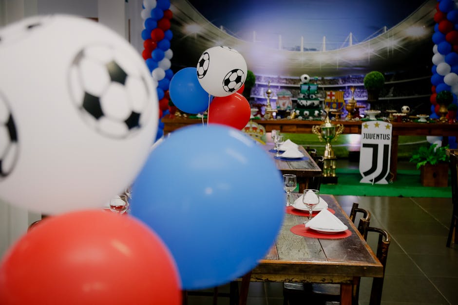 Colorful football party setup indoors with balloons and table settings, perfect for sports enthusiasts.