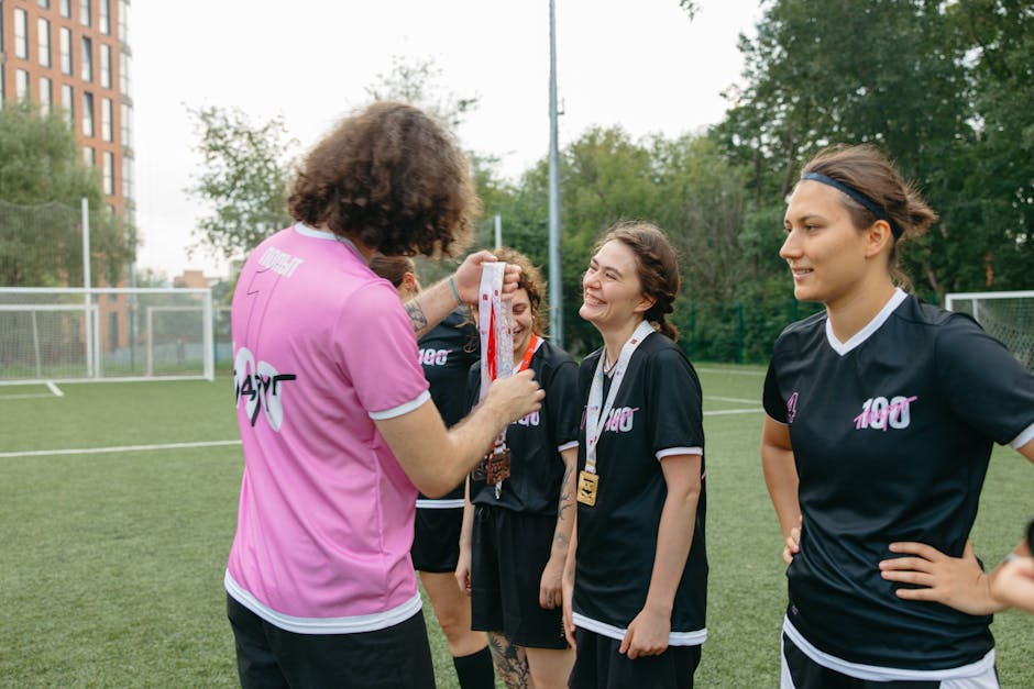A women's football team receiving medals on the field, celebrating their victory.