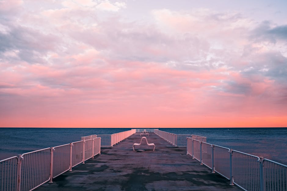 A serene dock extending into the ocean under vibrant sunrise skies, offering peace and solitude.