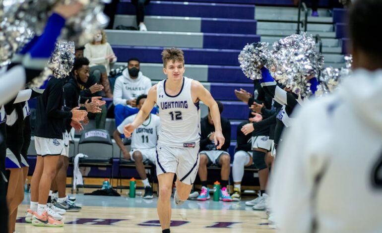 Young basketball player enters court surrounded by cheering teammates and fans.