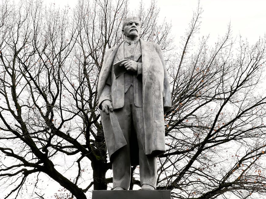 A towering statue of a historical figure set against bare trees in a park.