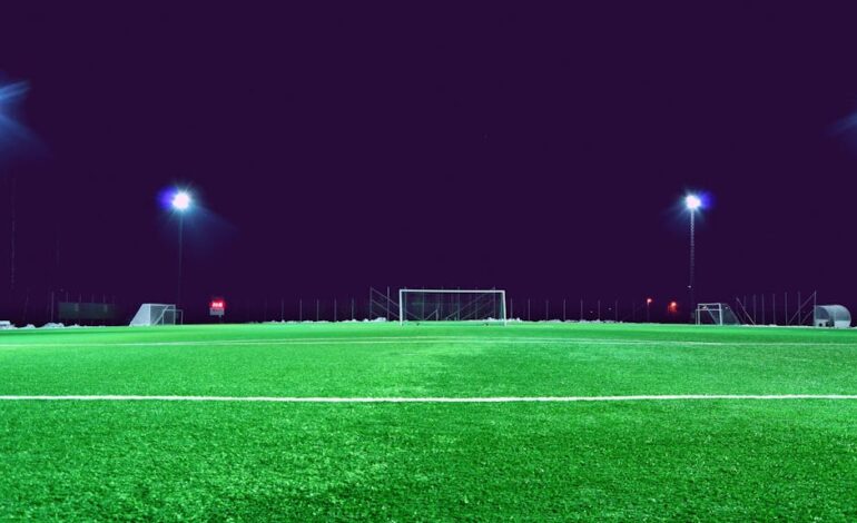 A brightly lit soccer field at night in Norrtälje, Sweden, showcasing green turf and stadium lights.
