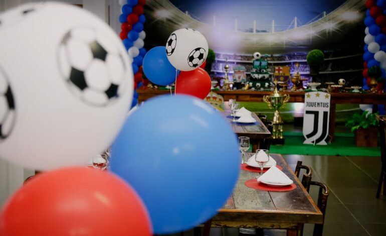 Colorful football party setup indoors with balloons and table settings, perfect for sports enthusiasts.