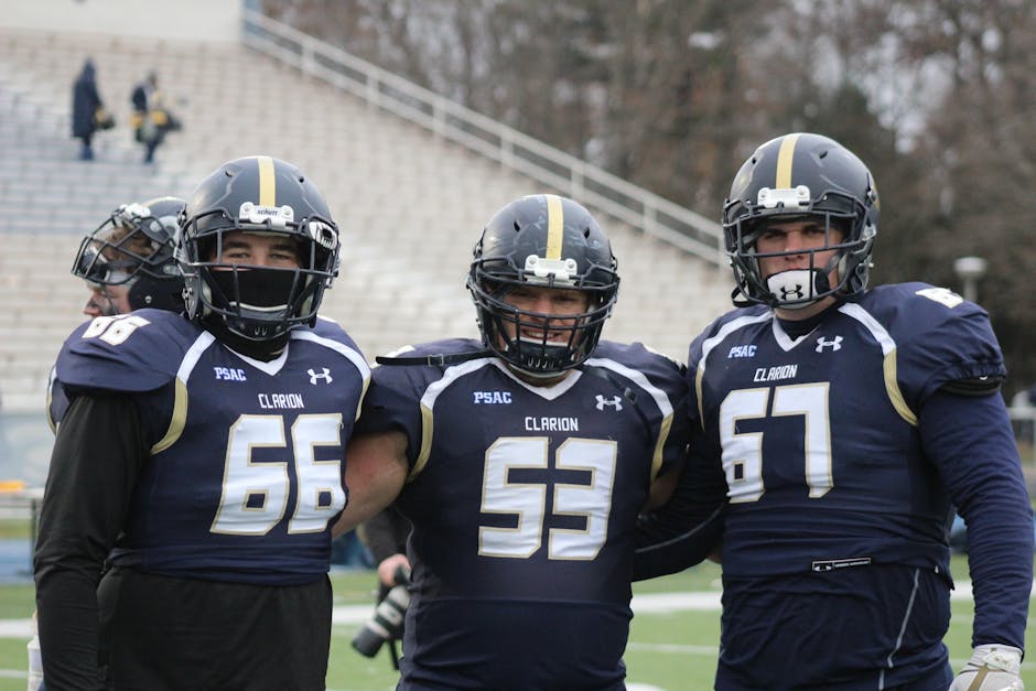 Three football players pose in uniforms at a college stadium, showcasing teamwork and sportsmanship.