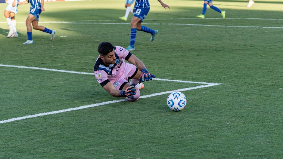 Goalkeeper makes a save on a sunny day during an intense soccer match.