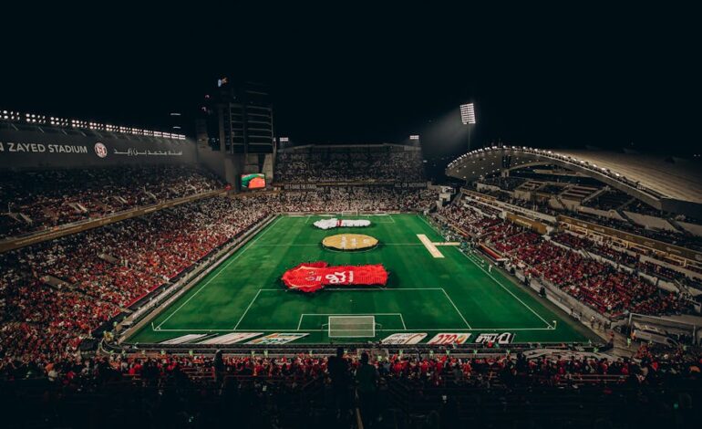 Aerial view of a lively football match at Zayed Stadium, showcasing fans and vibrant atmosphere.